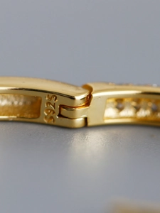 Macro detail of S925 sterling silver stamp and pave zircon stones on gold hoop earring