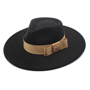 Detail of a black fedora hat with a golden ribbon and a vintage bee metal ornament