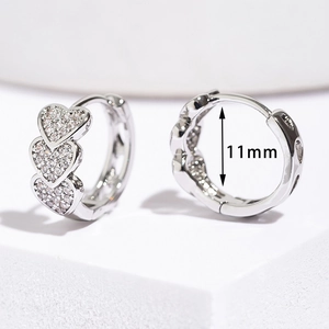 Macro shot of silver heart huggie earrings with cubic zirconia and 11mm inner diameter