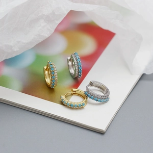Detailed view of gold and silver earrings with turquoise beads and sparkling cubic zirconia