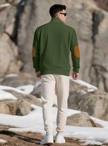 Detail of green knitted sweater with brown elbow patches and ribbed cuffs on male model