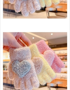 Detail of plush knitted children gloves featuring heart embroidery in pink and yellow