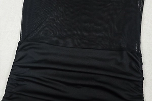 Detail of black mini dress featuring sheer mesh panel and ruched fabric texture