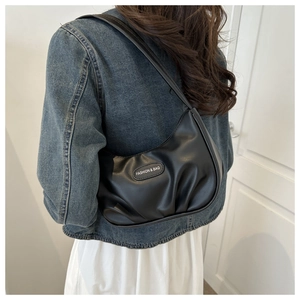 Détail d'un sac en similicuir plissé noir avec étiquette de mode et texture lisse