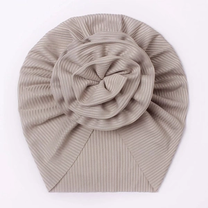 Detailed view of beige pleated baby turban hat with a decorative soft flower ornament