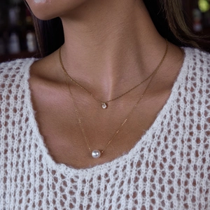 Détail du collier double rang doré avec pendentif cristal goutte et perle blanche