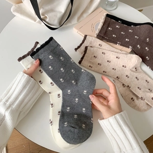 Détail de chaussettes en tricot fleuri vintage en blanc, gris et beige sur bureau