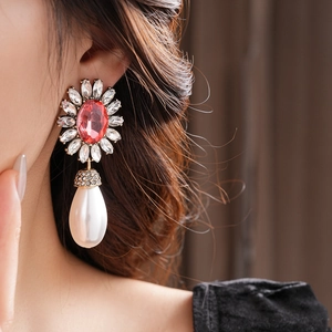 Détail de boucle d'oreille fleur de luxe avec gemme rose et perle goutte blanche portée