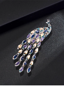 Close-up of a vintage peacock brooch with colorful crystals and long tassel details
