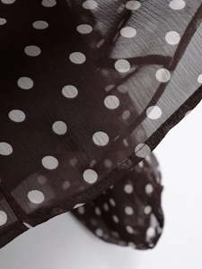 Close-up of semi-transparent black chiffon fabric with white polka dots and stitched hem