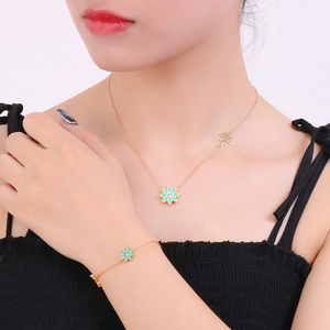Détail d'un ensemble collier et bracelet dorés avec pendentif fleur turquoise sur mannequin
