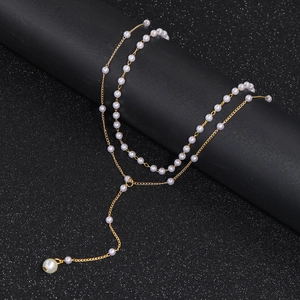 Detail of elegant gold-tone layered Y-necklace with imitation pearls on black display