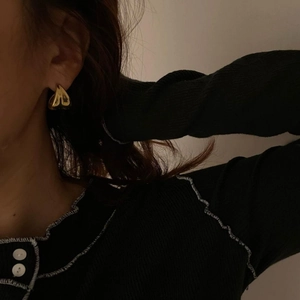 Close-up of golden 3D heart-shaped earrings on a model with a minimalist aesthetic