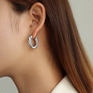 Woman wearing stylish silver twisted croissant hoop earrings in stainless steel