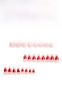 Macro shot of nude pink almond press-on nails with glittery red heart patterns