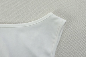 Detailed close-up of white pleated sleeveless dress neckline with premium stitching