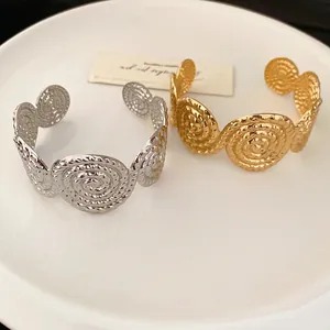 Textured gold and silver spiral open bangles presented on a minimalist white ceramic plate