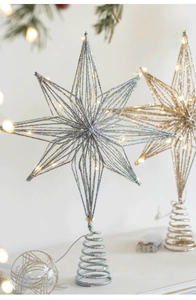 Close-up of glittery gold and silver Christmas tree star toppers with warm LED lights