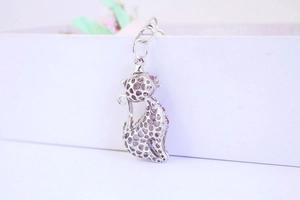 Detailed view of silver cat keychain featuring hollow spots and red crystal accents