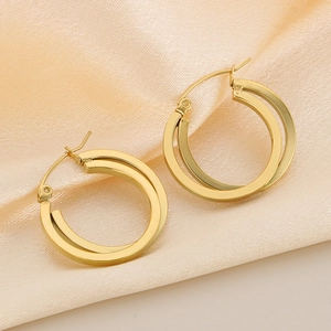 Elegant gold titanium steel crossover hoop earrings displayed on beige silk fabric