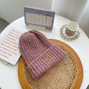Macro detail of purple pink chunky knit wool beanie with roll edge on wooden tray
