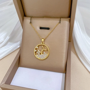 Elegant gold fishtail pendant necklace with sparkling stones in a beige jewelry box