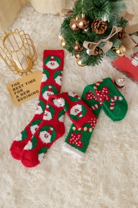 Nahaufnahme dicker Korallenfleece-Weihnachtssocken mit Weihnachtsmann- und Zuckerstangenmuster