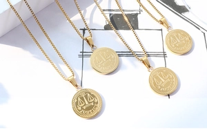 Detail of four gold Justice scales pendants on box chains with minimalist line background
