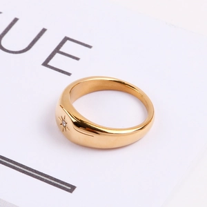 Détail d'une bague ovale polie à l'or avec un motif d'étoile orné d'un cristal brillant