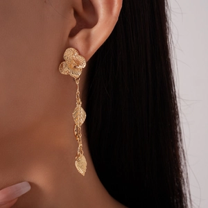 Detail of gold flower and leaf tassel earrings worn showing the elegant metal texture