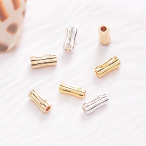Vue détaillée de perles d'espacement cylindriques texturées en or, argent et or rose pour bijoux