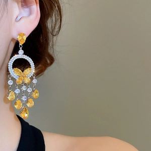 Detail of elegant chandelier tassel earring with butterfly pattern and crystals on model