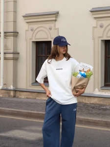 Dettaglio della t-shirt in cotone bianco con stampa ASSERTIVE e pantaloni blu casual