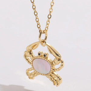 Macro shot of 14K gold-plated crab pendant with iridescent shell inlay and black eyes