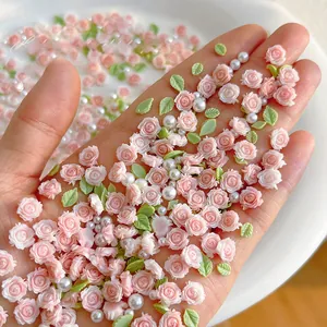Detailed view of pink resin roses and white pearls for DIY floral nail art decoration