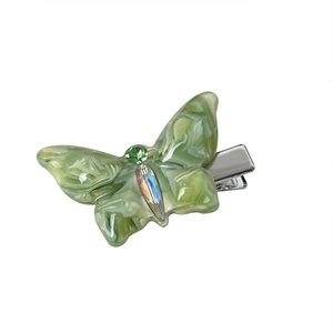 Barrette papillon 3D en acétate vert avec cristaux scintillants sur fond blanc