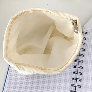 Borsa cosmetica trapuntata bianco crema con ricamo a cuore che mostra l'ampio interno