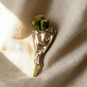 Makro-Detail der Blumenstrauß-Brosche mit goldener Metalltextur und gelben Knospen
