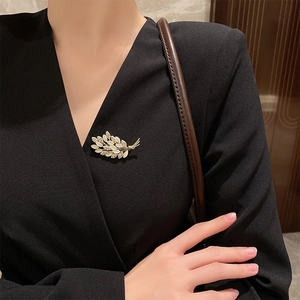 Elegant gold wheat brooch with cat eye stones and rhinestones worn on a model's blazer