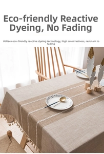 Detail of linen-blend tablecloth featuring beige patchwork, embroidery, and white tassels