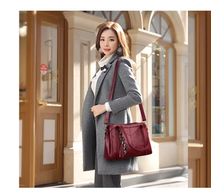 Close-up of burgundy leather crossbody bag with V-shaped stitching and tassel charm