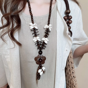 Detail of bohemian necklace with dark wood beads and white shell floral pendant