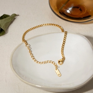 Classic 18K gold plated stainless steel 3mm Cuban link anklet on a white ceramic dish