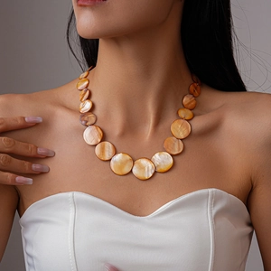 Detail of handmade shell beaded necklace with orange gradient discs on female model