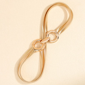 Detail view of gold elastic metal belt with double circle buckle on textured surface