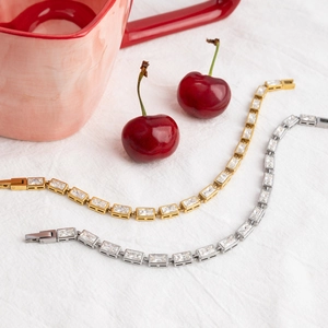 Detail of rectangular zircon bracelets in gold and silver finish on linen fabric