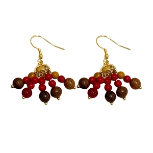 Bohemian drop earrings featuring wood and red glass beads with gold hooks on white background