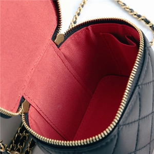 Detail view of the black quilted leather bag showing red lining and gold hardware zippers