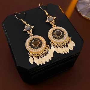 Détail de boucles d'oreilles vintage en or avec pierre noire, perles et feuilles