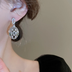 Detail of snake head drop earring with white zircons and green gemstone eyes
